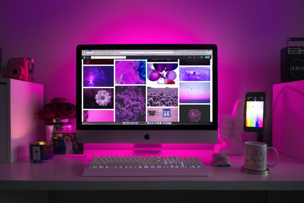 Website Refresh. Computer with multiple image examples on a pink background; Harv Communications