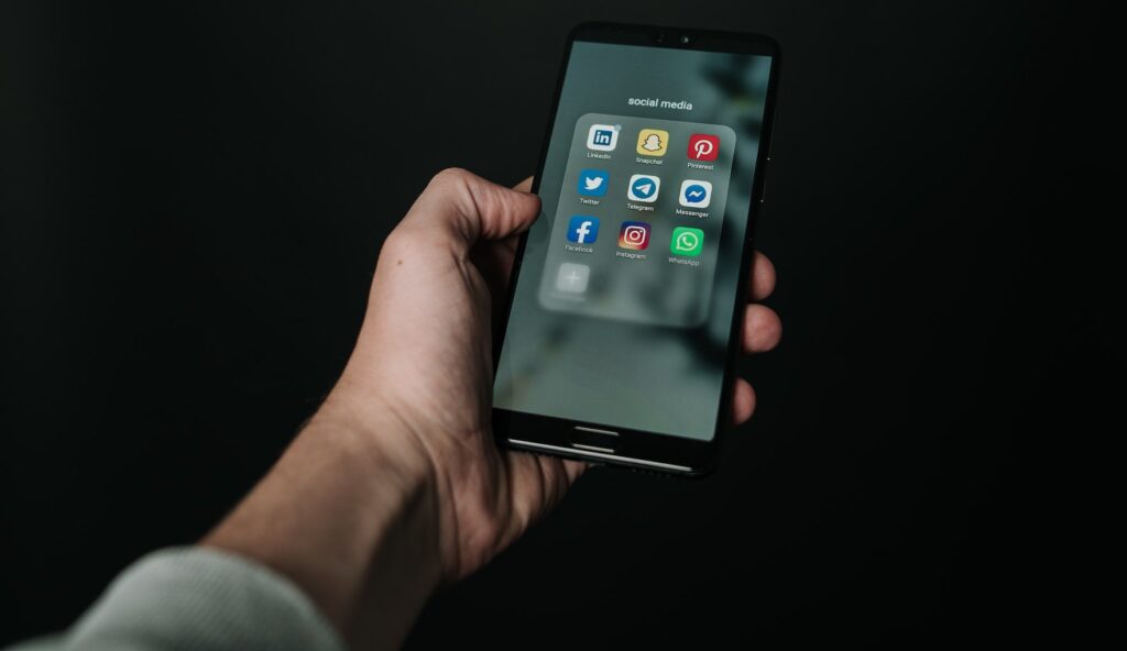 person holding phone with Social Media icons; Tips & Tricks for Social Media by Harv Communications